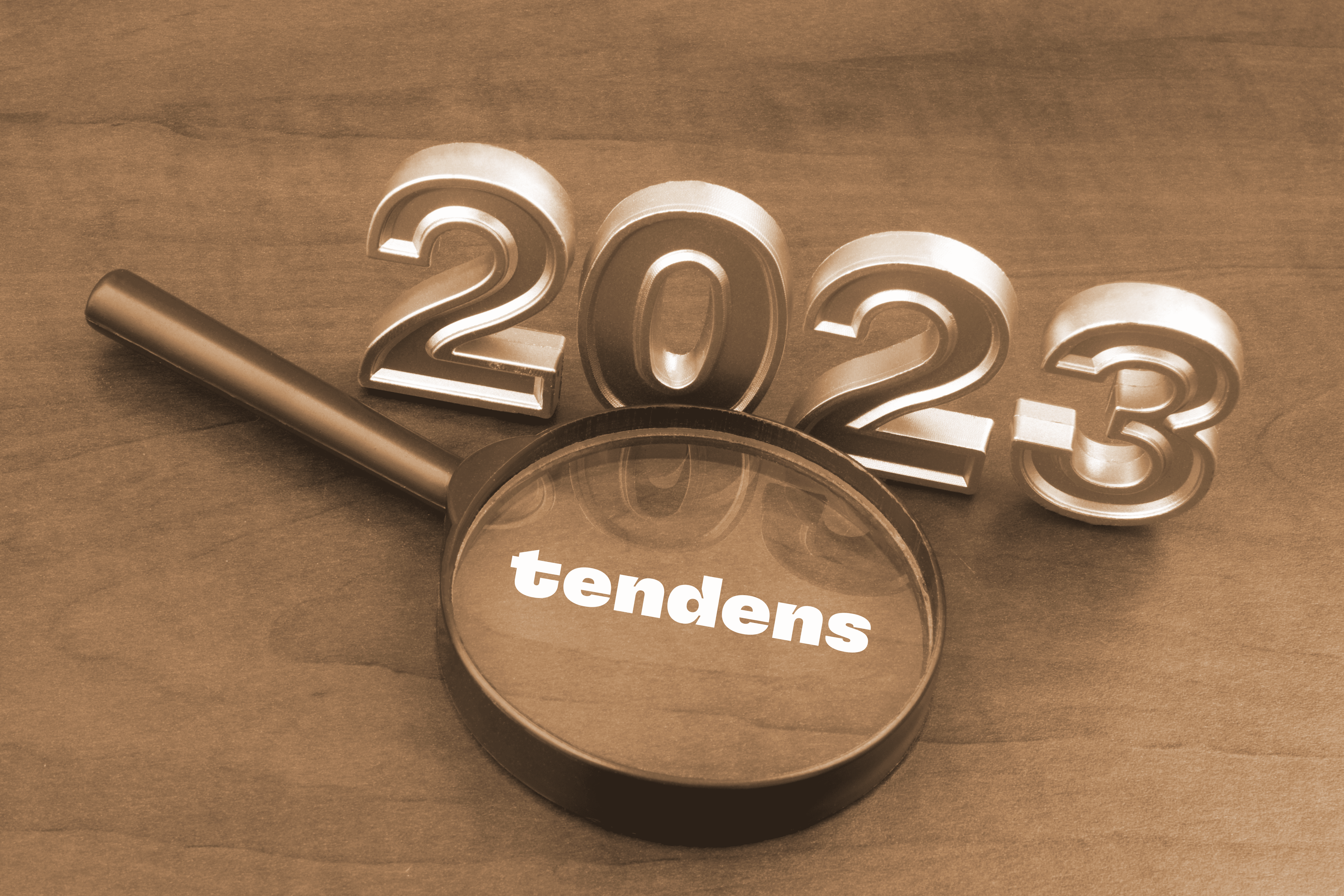 Årstallet 2023 vises i gullskrift, sammen med teksten Tendens inni et forstørelsesglass