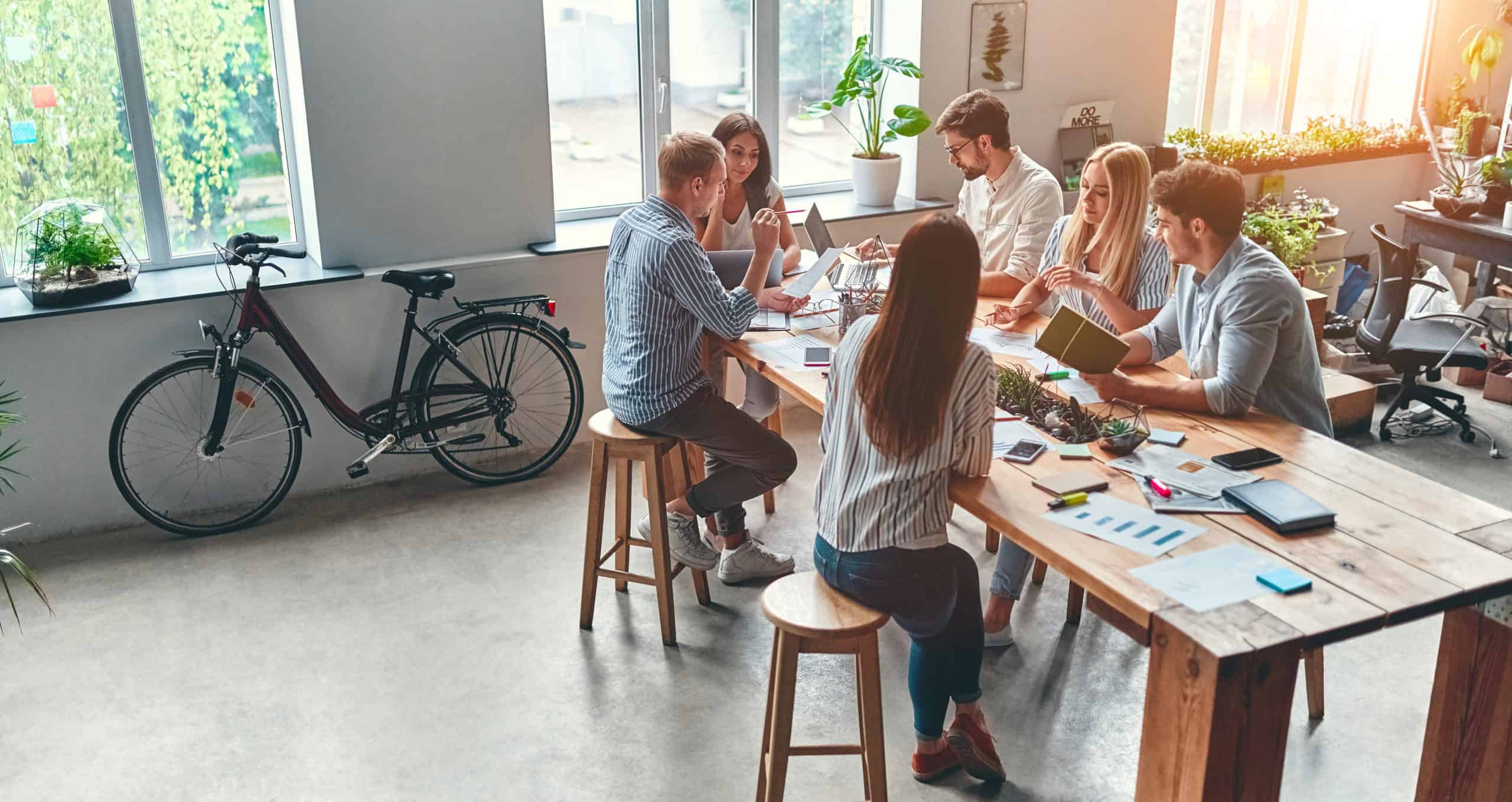 Flere unge mennesker sitter rundt et bord og diskuterer.